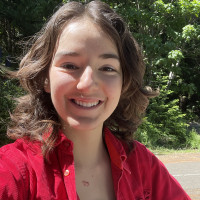 Skylin Alcorn smiling outside wearing a red jacket.
