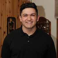 Luke smiling, wearing a black polo shirt.