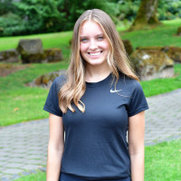 Arielle smiling outside. She is wearing a black tshirt.