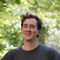 John smiling outside, wearing a dark tshirt.