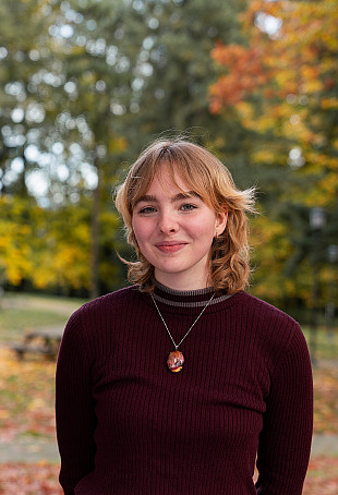 Avarie posing outside the Manor House, wearing a black sweater.