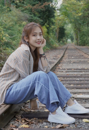 Evangeline, sitting on railroad tracks, smiling into the camera.