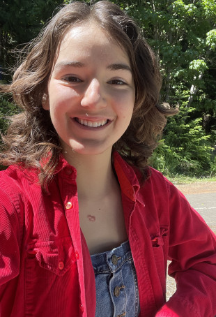 Skylin Alcorn smiling outside wearing a red jacket.