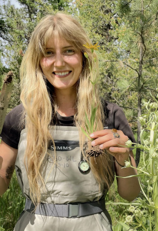 Alex posing outside with a yellow flower she dug up.
