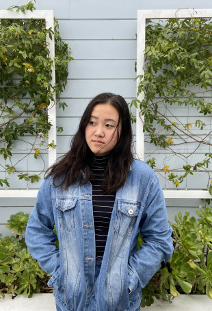 Alys, looking upward, standing in front of a vine-covered wall. Student-supplied profile photo due to COVID-19. Thank you, Alys!
