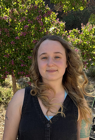 Kathryn smiling outside, wearing a black tank top.