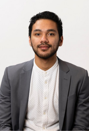 Farjad portrait. He is wearing a white button-up shirt and a grey jacket.