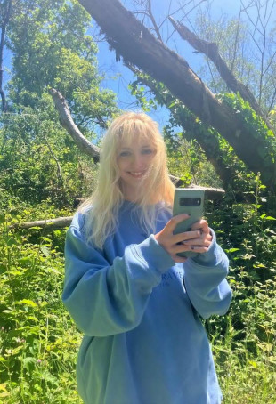 Valerie posing outside wearing a blue long-sleeved sweatshirt.