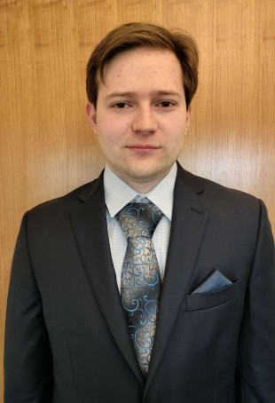 Christopher wearing a dark suit with a tie.