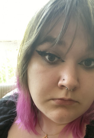Close up of Maddie. They have brown hair with bangs and dyed pink tips.