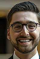 Alex smiling at the camera, wearing glasses.
