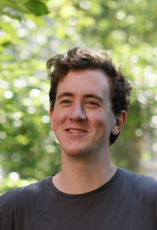 John smiling outside, wearing a dark tshirt.