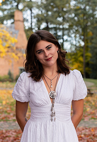 Amber posing outside the Manor House wearing a white dress.