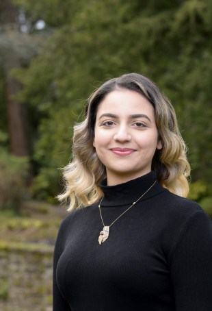 Jana smiling outside wearing a black turtleneck top and a necklace.