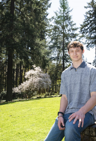 Sebastian posing outside. He is wearing a blue polo shirt and blue jeans.