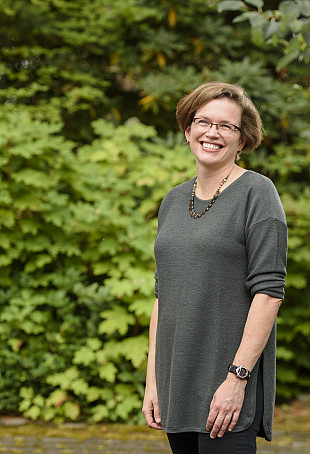 Anne posing outside, wearing a gray sweater.