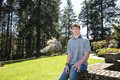 Sebastian posing outside. He is wearing a blue polo shirt and blue jeans.