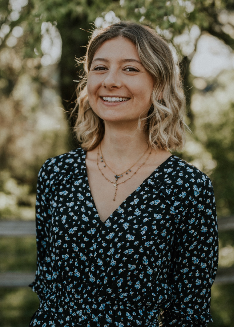 Nicole, smiling, standing in front of trees on a sunny day. Processed with VSCO with j2 preset. Student-supplied profile photo due to COV...