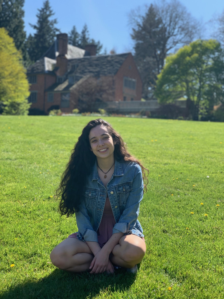 Juliana, smiling, sitting on the grass in front of the Manor House on a sunny day. Student-supplied profile photo due to COVID-19. Thank ...
