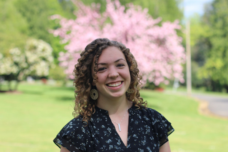 Ellie Miller, standing outside, smiling on a sunny day.