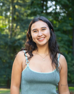 Lucinda smiling and posed with a forested background