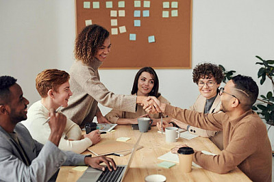    “An intern shaking hands with a co-worker during an office meeting 