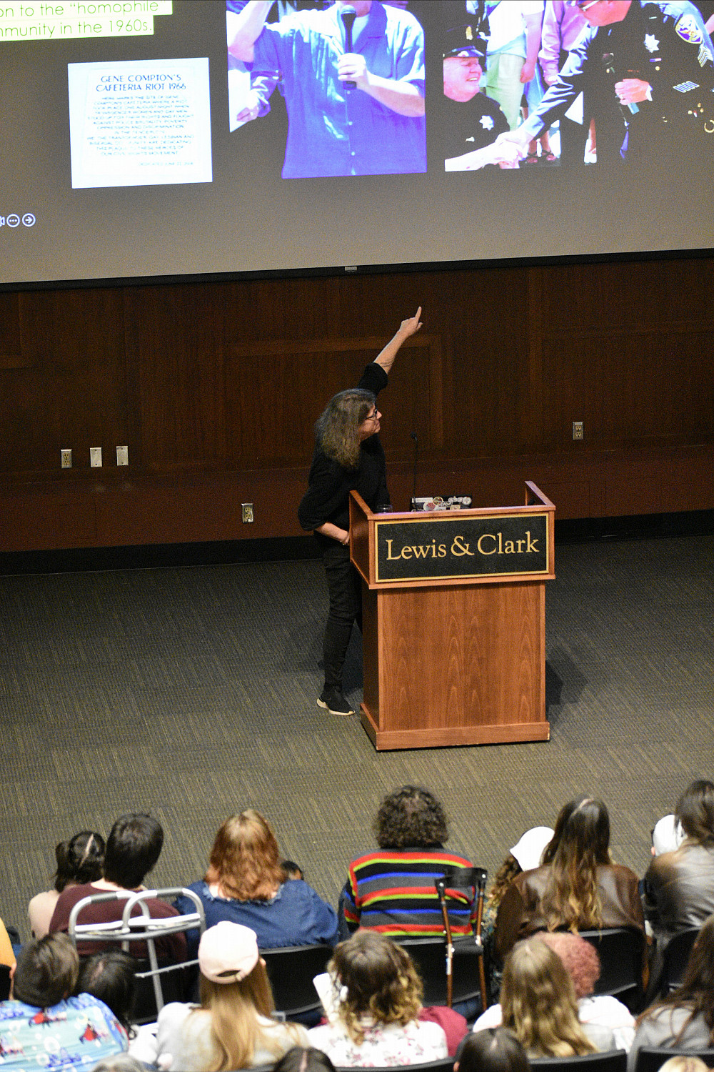 woman at podium pointing to image on screen behind her