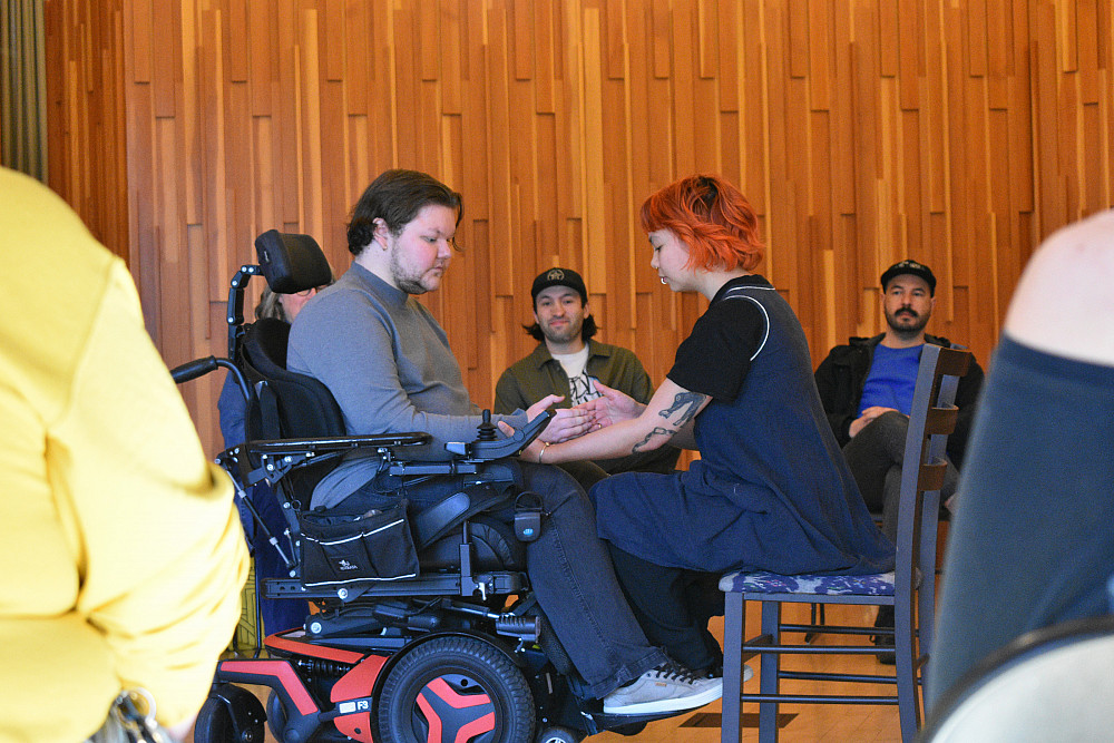 Seater person touching hand of person in wheelchair in front of them