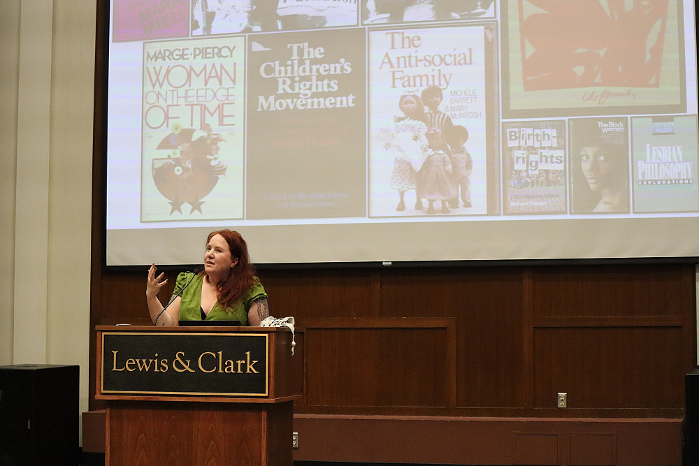 Female at podium, in front of large screen with images