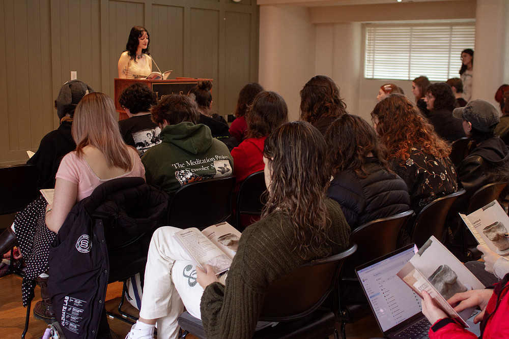 Seated students, all reading the same book.