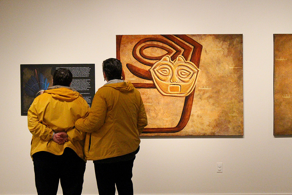 two adults looking at art posted on the wall.