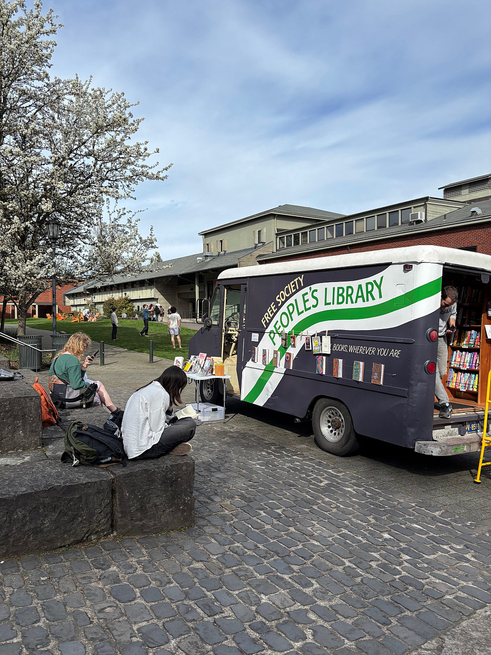 Colorful van converted into bookmobile parked on college campus.