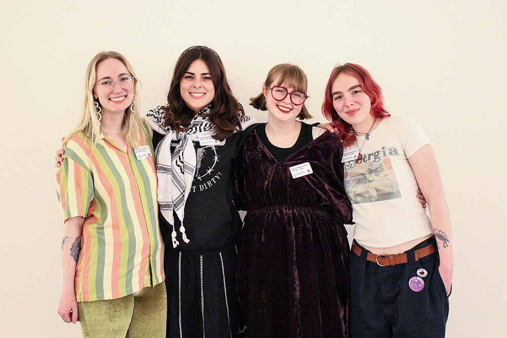 Four stmiling women posing for a photo standing arm-in-arm
