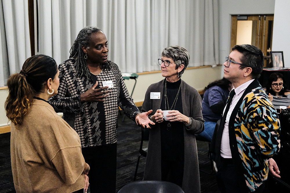 Four individuals standing, enagaging in conversation