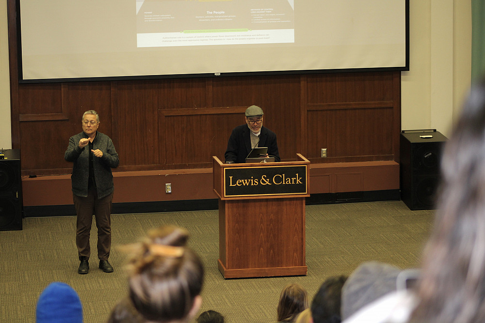 Sign language interpreter to the left of presenter speaking at podium