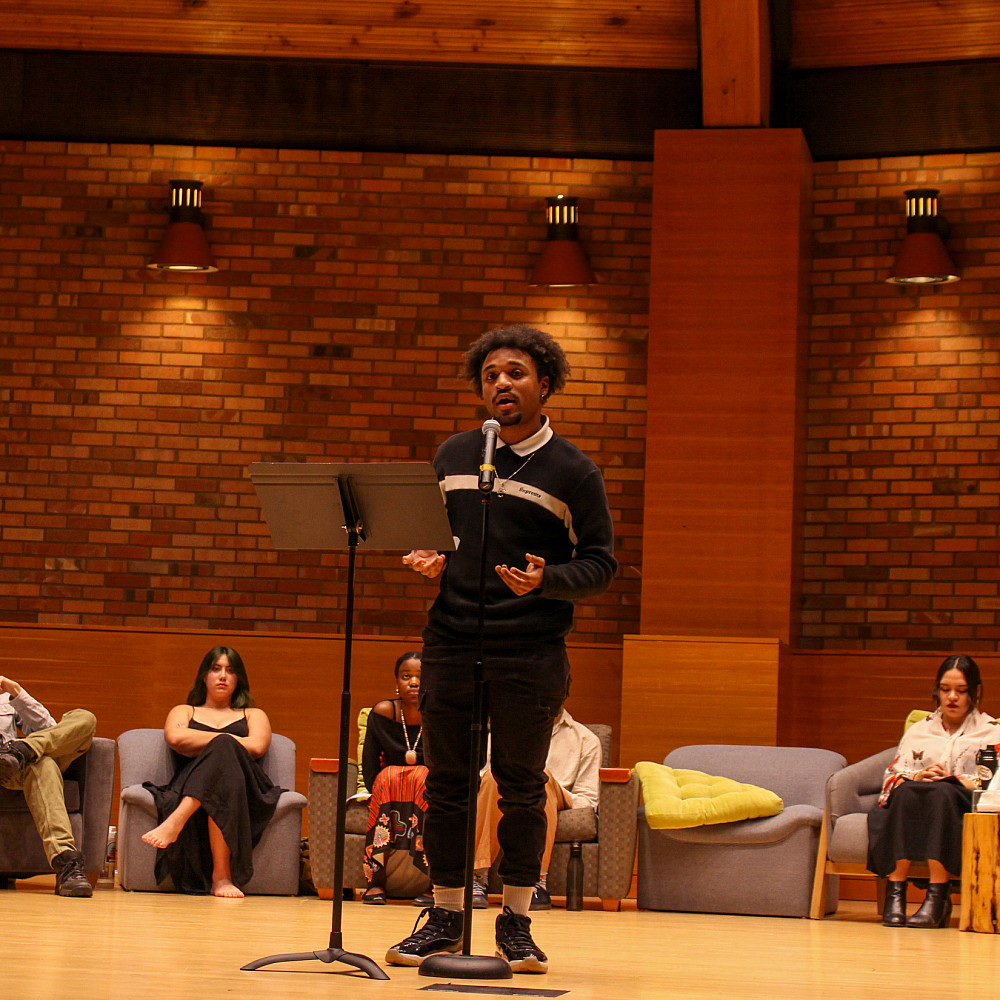 A student standing on stage in Agnes Flanagan Chapel, speaking into a microphone