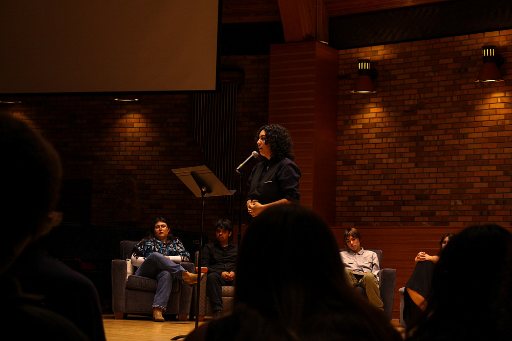 A student standing on stage in the Agnes Flanagan Chapel, speaking into a microphone