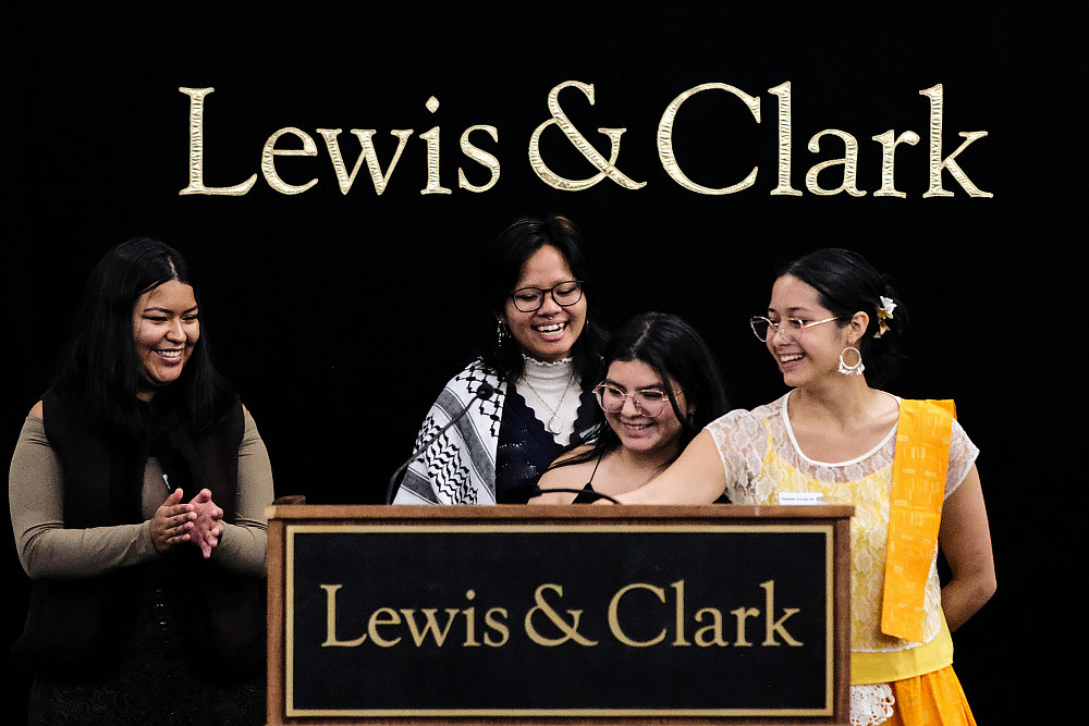 The four co-chairs of the symposium standing at a podium, smiling