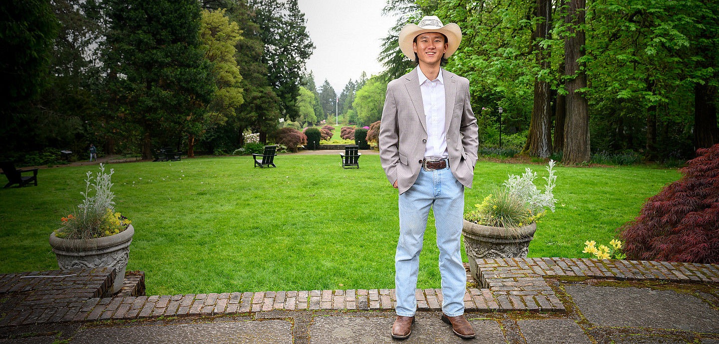 Victor posing outside, wearing a cowboy hat, blazer, and jeans.