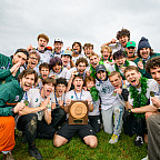 A group of student-athletes cheering and holding a trophy.