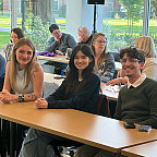 Three students sit at a table.