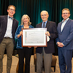 Greta posing with her award along with three other people.
