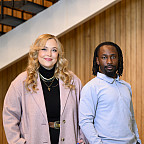 Alessandra and John posing for the camera in front of a staircase.