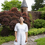 Azucena posing outside, wearing a white dress and glasses.