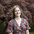 Alexandra posing outside, wearing a floral dress.
