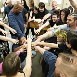 L&C students and CRCI Adults in Custody stand in a circle and stack their hands together.