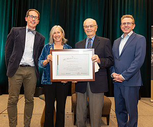 Greta posing with her award along with three other people.