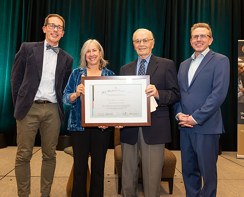 Greta posing with her award along with three other people.