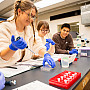 Students using science equipment and wearing blue gloves.