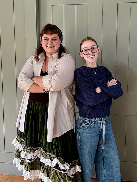 2 college students standing back to back with arms crossed